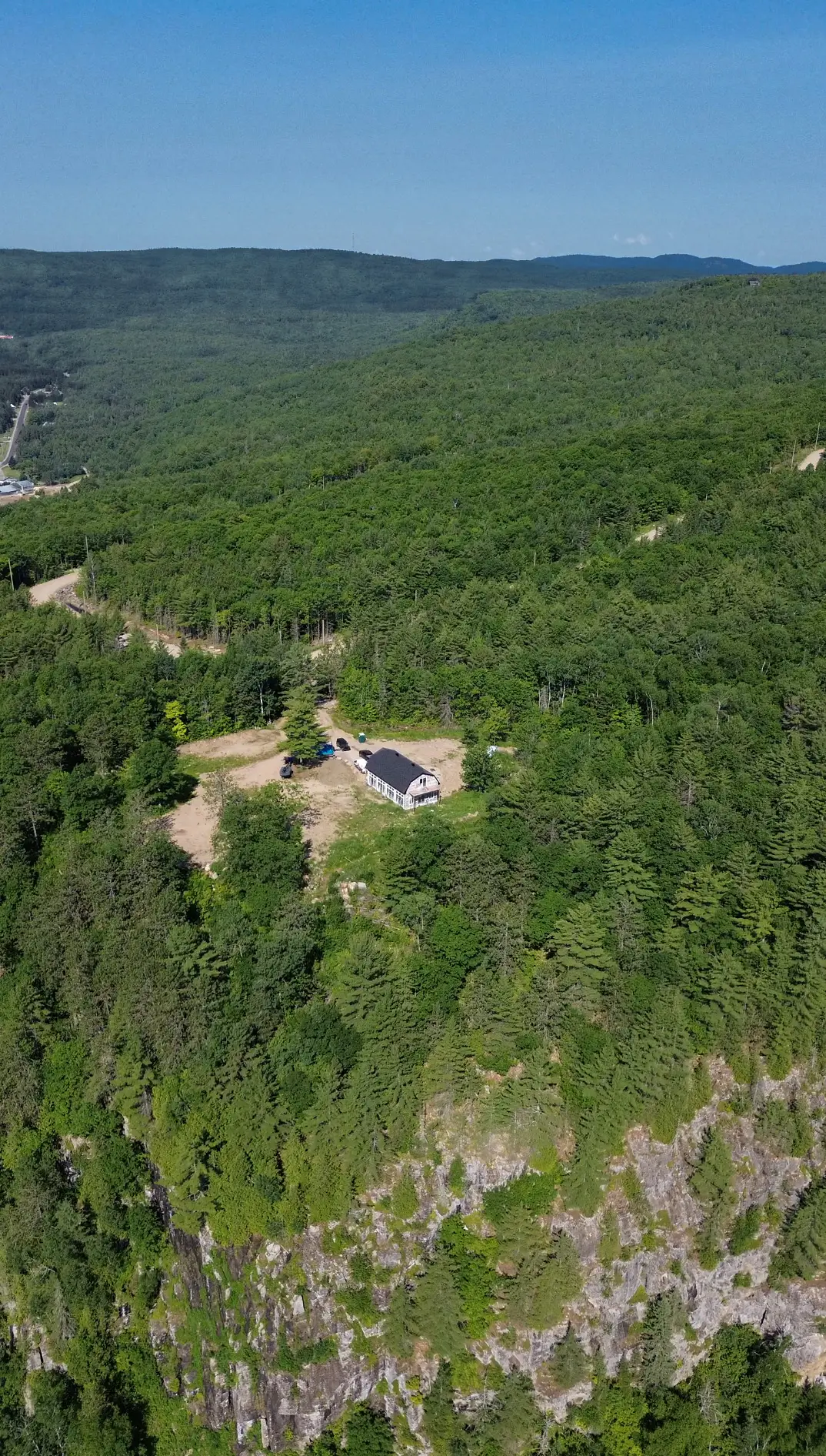 Vue aérienne du domaine : une maison au sommet d'un promontoire boisé